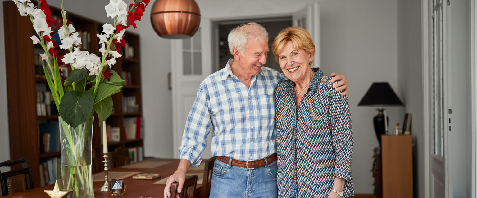 Ein Mann und eine Frau stehen zufrieden in einem Wohnzimmer.