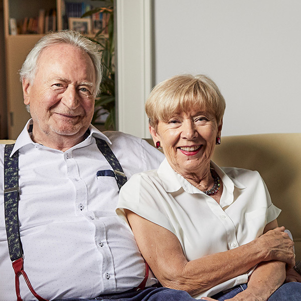 Ein älteres Paar sitzt gemütlich auf einem Sofa.