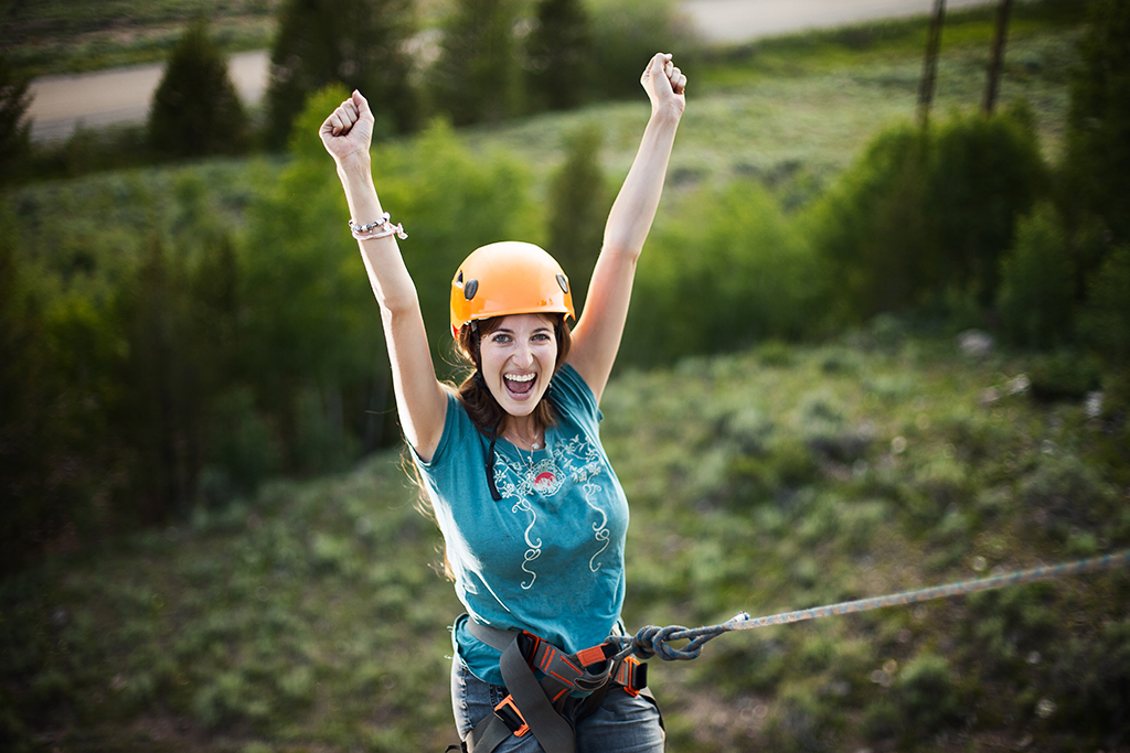 Eine junge Frau reckt die Arme in die Höhe. Sie lächelt und strahlt Freude über den Erfolg aus.
