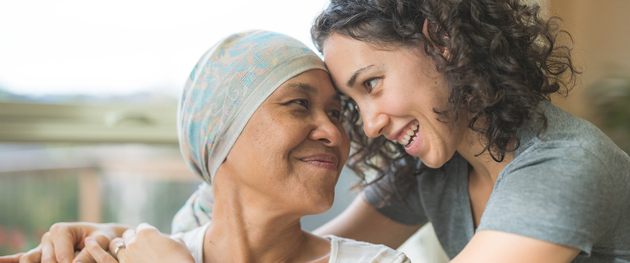 Eine junge Frau umarmt eine ältere Frau, die ein Tuch um den Kopf geschlungen hat.
